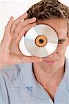 Portrait of a mid adult man peeking through a CD