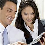 Close-up of a businessman and a businesswoman reading a book