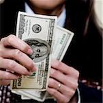 Close-up of a businesswoman holding one hundred dollar bills