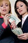 Low angle view of two businesswomen holding American paper currency