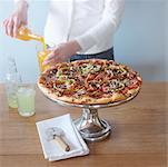 Woman Pouring Juice with Pizza on the Table