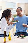 Couple in Kitchen Eating Salad and Drinking Wine