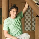 Portrait d'un jeune homme assis sur le porche souriant