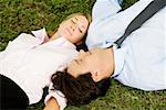 Close-up of a businesswoman and a businessman lying on the grass
