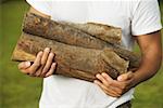 Mid section view of a young man holding firewood