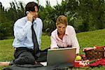 Gros plan d'un homme et une femme d'affaires travaillant sur un ordinateur portable dans le parc