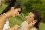 Close-up of two teenage girls holding an MP3 player listening to music