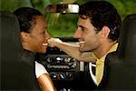 Young woman and a mid adult man sitting in a car looking at each other