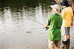 Rear view of two brothers fishing near a lake