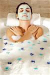 Erhöhte Ansicht einer jungen Frau mit einer Gesichts-Maske in einer Badewanne