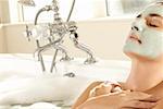 Gros plan d'une jeune femme portant un masque du visage dans une baignoire