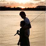 Silhouette d'un père et son fils transportant une canne à pêche
