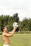 Side profile of a mid adult man holding a soccer ball