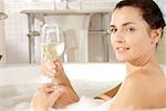 Porträt einer jungen Frau mit einem Glas Wein in der Badewanne