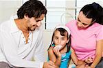 Close-up of a young couple looking at their daughter eating a pastry