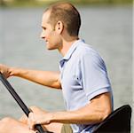 Side profile of a young man kayaking in a lake