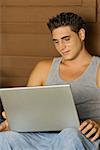 Close-up of a young man using a laptop and smiling