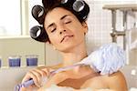 Close-up of a young woman scrubbing her shoulder with a bath sponge