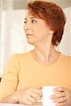 Close-up of a senior woman holding a cup of coffee looking sideways