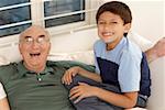 Portrait of a boy sitting with his grandfather on a couch