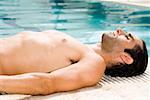 Side profile of a mid adult man sunbathing at the poolside