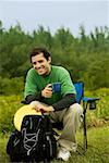 Portrait d'un homme adult moyen assis sur une chaise, tenant une tasse de café