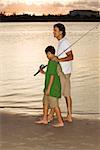 Side profile of a boy walking with his father on the beach