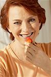 Portrait of a senior woman holding a strawberry