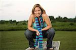 Portrait of a mature woman crouching on a picnic table