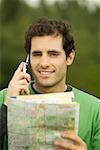 Portrait d'un homme adult moyen parler sur un téléphone mobile tenant une carte