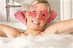Portrait d'une jeune femme portant un masque pour les yeux dans une baignoire