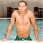 Porträt eines jungen Mannes, der an den Rand des Schwimmbads gelehnt