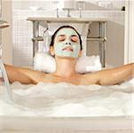 Close-up of a young woman with a facial mask relaxing in a bathtub