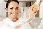 Portrait of a young woman using a bath sponge on her arm