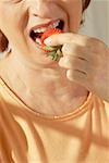Mid section view of a senior woman eating a strawberry