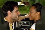 Young woman and a mid adult man sitting in a car looking at each other