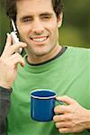 Close-up of a mid adult man talking on a mobile phone holding a coffee cup