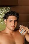 Portrait d'un jeune homme torse nu tenant une bouteille d'eau
