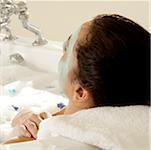 Close-up of a young woman wearing a facial mask in a bathtub