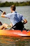 Vue arrière d'un jeune homme en kayak dans un lac