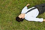 High angle view of a businessman lying on the grass