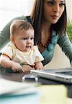 Mère avec bébé sur ses genoux à l'aide d'ordinateur portable