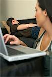 Woman Working at Computer and Man Napping on Couch