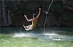 Man on Rope Swing by Lake