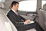 Businessman Using Laptop Computer in Car