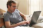 Homme utilisant un ordinateur portable dans le lit