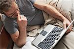 Mann mit Laptop-Computer im Bett
