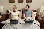 Couple with Laptops in Bed