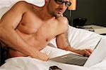 Man lying on bed, using laptop