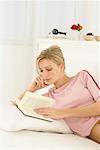 Frau liegend auf einem Bett, ein Buch zu lesen